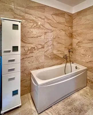 a bathroom with a white tub and a cabinet at Apartament Rafailovici Budva in Budva