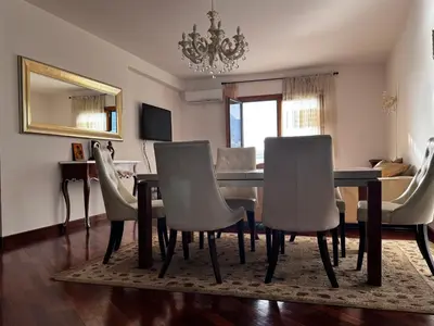 a dining room with a table and white chairs at Apartament Rafailovici Budva in Budva