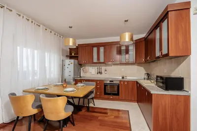 a kitchen with a wooden table and chairs in it at Adriatic Lux Apartment in Bar