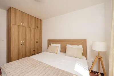a bedroom with a bed and a wooden cabinet at Adriatic Lux Apartment in Bar