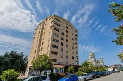 a tall building with cars parked in a parking lot at Adriatic Lux Apartment in Bar