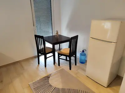 a dining room table with two chairs and a refrigerator at Big Blue Apartment in Ulcinj