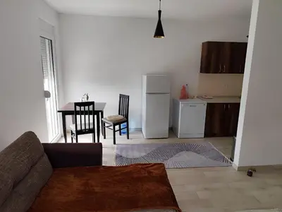 a living room with a couch and a kitchen with a table at Big Blue Apartment in Ulcinj