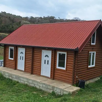 a log cabin with white doors and a red roof at Cottage Kolomza in Ulcinj