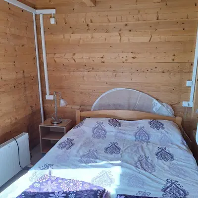 a bed in a room with a wooden wall at Cottage Kolomza in Ulcinj