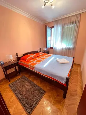 a bedroom with a bed with an orange comforter and a window at Apartman Darija in Bar