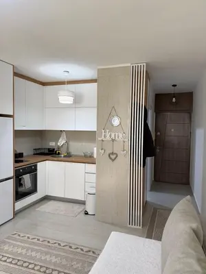 a kitchen with white cabinets and a door with the word evolve at Sanja apartman in Bar
