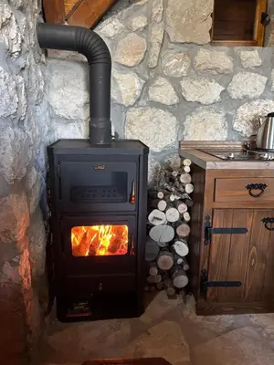 a stove with a fire in a stone wall at Montenegro Rustic House II in Bjeloši