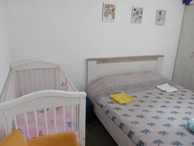 a bedroom with a crib and a bed with a yellow towel at Piano Seaside in Ulcinj
