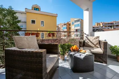 a patio with wicker chairs and a table on a balcony at Bozovic Apartmani in Budva