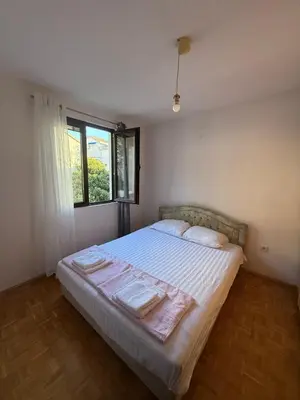 a bedroom with a bed with white sheets and a window at Bozovic Apartmani in Budva