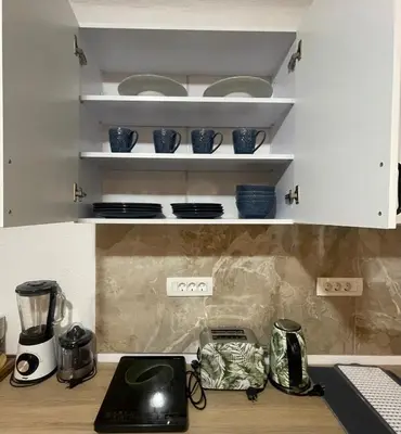 a kitchen with white cabinets and blue bowls on shelves at Kotor Old Town Cozy Escape in Kotor