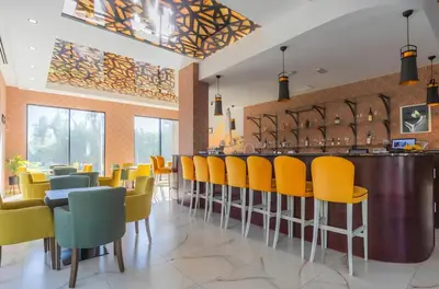 a restaurant with yellow chairs and a bar at Apartment San Riviera in Bar