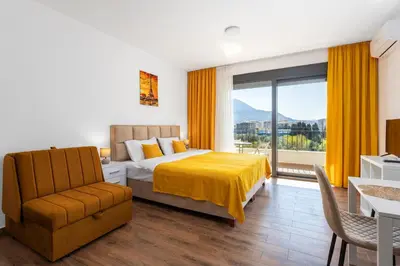 a bedroom with a bed and a chair and a window at Apartment San Riviera in Bar