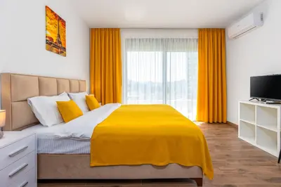 a bedroom with a bed with yellow sheets and a window at Apartment San Riviera in Bar