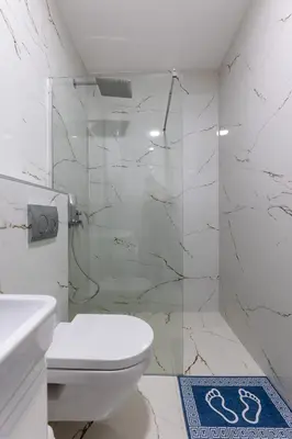 a white bathroom with a toilet and a shower at Sea Breeze apartment in Bar