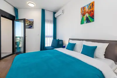 a bedroom with a large bed with blue sheets at Sea Breeze apartment in Bar