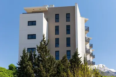 a white building with trees in front of it at Sea Breeze apartment in Bar