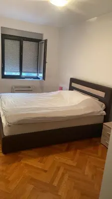 a large bed in a room with a wooden floor at 2 bedroom apartment blok 9 in Podgorica