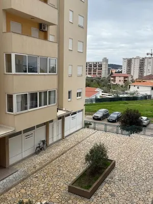 an apartment building with cars parked in a parking lot at Stan 60m2 in Bar