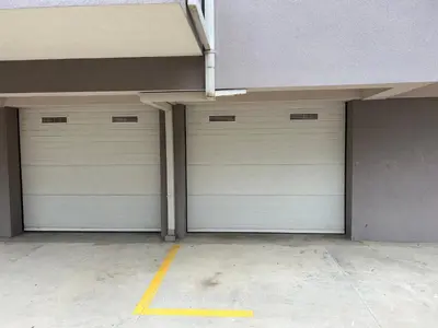 two white garage doors in a building at Enyana Family Apartment in Dobrota
