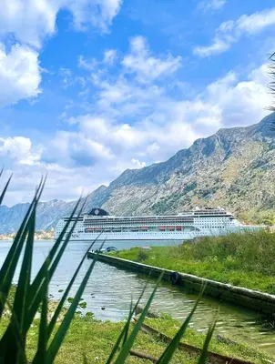 a cruise ship on a river with mountains in the background at Apartment Studio Z&M in Kotor