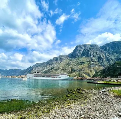 a cruise ship on the water with mountains in the background at Apartment Studio Z&M in Kotor