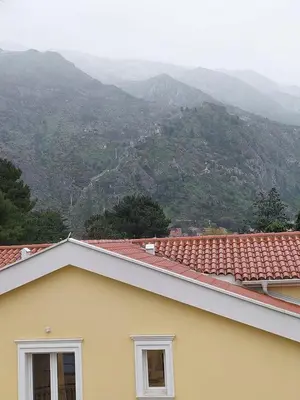 a yellow house with mountains in the background at Bonaca Home Kotor in Kotor