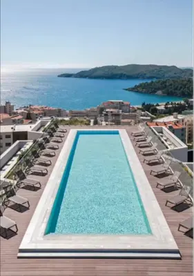 a swimming pool with lounge chairs and the ocean at Vuelo Sobre by In Property in Becici