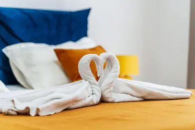 two towel swans sitting on a table in a hotel room at Luna skyline sea view apt in Budva