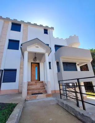 a white house with a door and stairs at Green Castle in Kunje