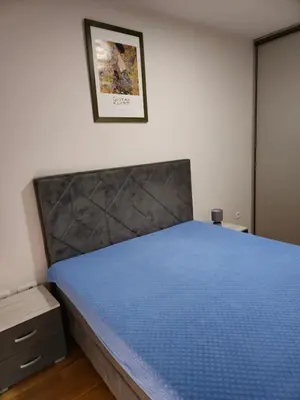 a bedroom with a bed with a blue bedspread at Central Point apartment in Podgorica