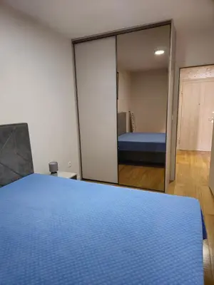 a bedroom with a blue bed and a mirror at Central Point apartment in Podgorica