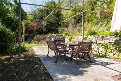 a patio table and chairs in a garden at Glanz Antique Paradise near the Sea in Kotor