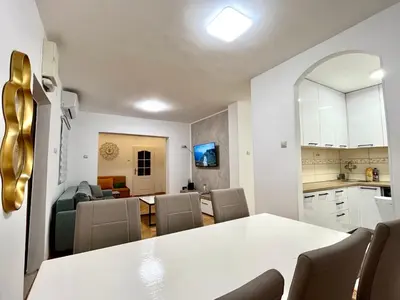 a kitchen and living room with a white table and chairs at Three bedroom apartment Budva in Budva