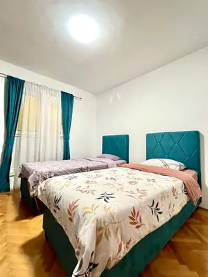 two beds in a bedroom with blue curtains at Three bedroom apartment Budva in Budva