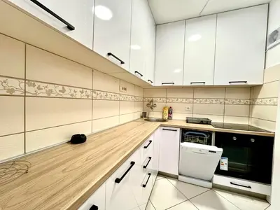 a kitchen with white cabinets and a wooden floor at Three bedroom apartment Budva in Budva