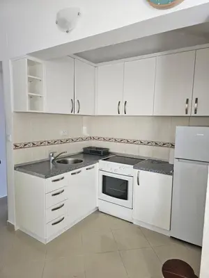 a white kitchen with white cabinets and a sink at Tirke Apartment in Becici