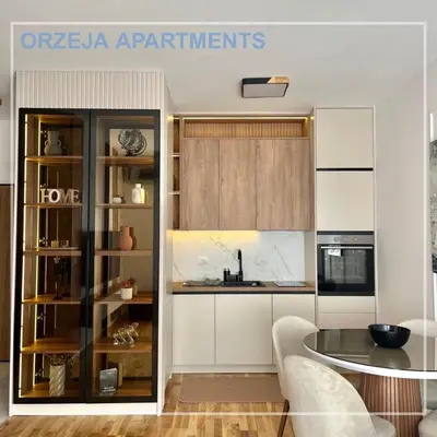 a kitchen with white cabinets and a table at Orzeja apartments in Ulcinj