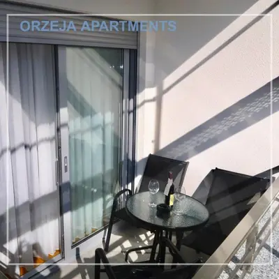 a table with a bottle of wine on a balcony at Orzeja apartments in Ulcinj