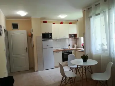 a kitchen with white cabinets and a table and chairs at Apartment Nikolic Kotor in Kotor