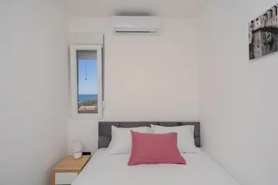a bedroom with a white bed with a pink pillow at Aurora Apartments in Bar