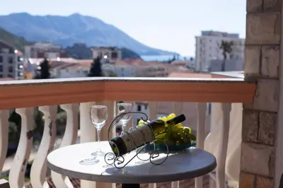 a table with a wine bottle and wine glasses on a balcony at Villa Iper in Budva