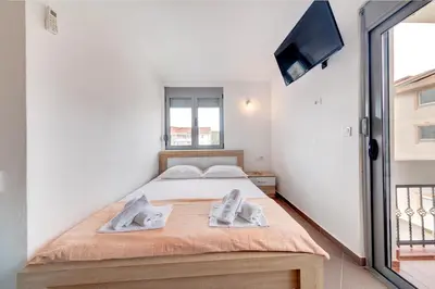 a bedroom with a bed and a flat screen tv at Delfin Apartments in Sutomore