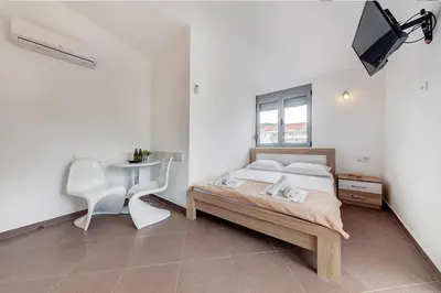 a bedroom with a bed and a table and a tv at Delfin Apartments in Sutomore