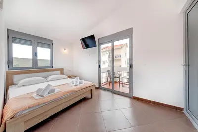 a bedroom with a large bed and a balcony at Delfin Apartments in Sutomore