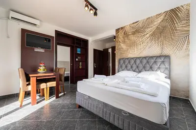 a bedroom with a bed and a table and a television at Delfin Apartments in Sutomore
