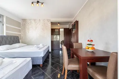 a hotel room with two beds and a dining table at Delfin Apartments in Sutomore