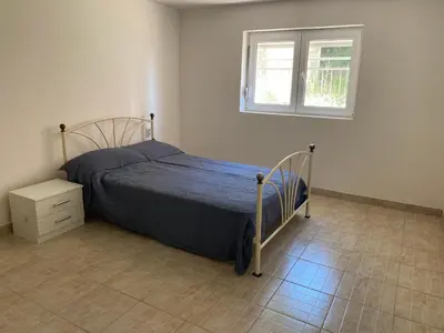a bedroom with a bed with a blue comforter and a window at Pink Holiday House Sutomore in Zankovići