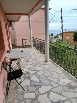 a patio with a table and chairs on a balcony at Pink Holiday House Sutomore in Zankovići